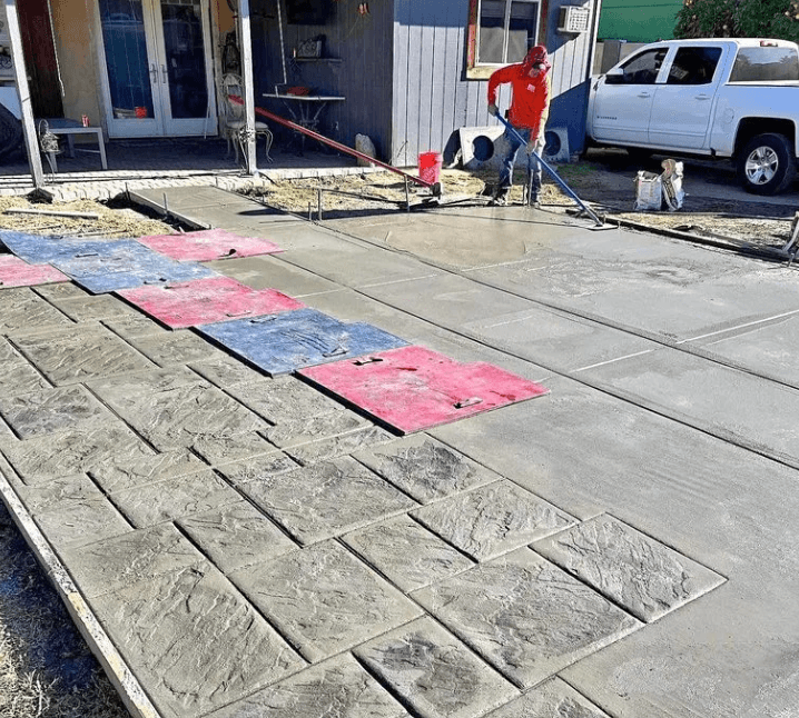 Crew finishing a stamped concrete driveway with stone-pattern texture mats
